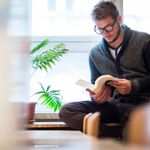 Young man reading a book in library Young man reading a book in library